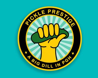 May include: A yellow and black circular sticker with the text "Pickle Prestige" and "A Big Dill in PGH" in a yellow circle with a yellow hand holding a green pickle.