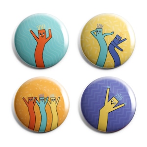 May include: Four round pinback buttons featuring cartoon inflatable tube men in various poses. The buttons have different colored backgrounds and patterns. One button features a single orange tube man with a blue background. Another button features two tube men, one blue and one purple, with a yellow background. A third button features three tube men, one orange, one blue, and one yellow, with an orange background. The final button features a single yellow tube man with a purple background.