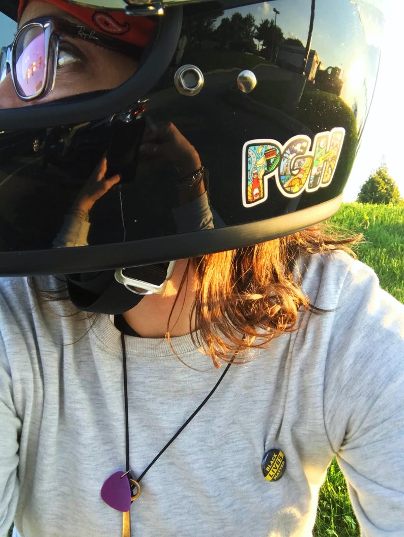 K&ouml;nnte beinhalten: Eine Person tr&auml;gt einen schwarzen Motorradhelm mit einem bunten Aufkleber, auf dem "PGH" steht. Die Person tr&auml;gt auch einen grauen Pullover mit einer schwarzen Halskette und einem schwarzen Knopf, auf dem "Black Lives Matter" steht.