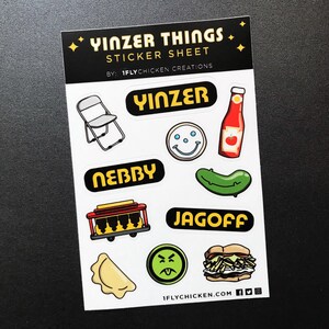 K&ouml;nnte beinhalten: Ein Aufkleberbogen mit verschiedenen Designs zum Thema Pittsburgh, darunter ein Klappstuhl, eine Gurke, ein Hotdog, ein Smiley und die W&ouml;rter "Yinzer", "Jagoff" und "Ne'erby". Der Bogen ist wei&szlig; mit schwarzem und gelbem Text und Grafiken. Der Text "Yinzer Things Sticker Sheet" befindet sich oben auf dem Bogen, und der Text "1flychicken.com" befindet sich unten.