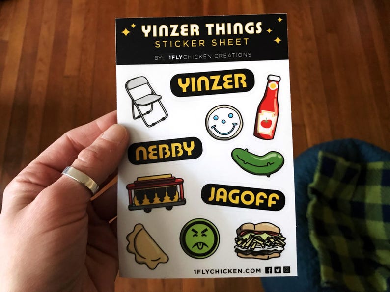 K&ouml;nnte beinhalten: Ein Aufkleberbogen mit dem Titel "Yinzer Things Sticker Sheet" von "1FlyChicken Creations". Der Bogen enth&auml;lt verschiedene Aufkleber mit Pittsburgh-Slang-Begriffen, darunter "Yinzer", "Jagoff", "Nebby" und ein Smiley mit drei Punkten. Es gibt auch einen Aufkleber einer Ketchupflasche, einer Gurke, eines Klappstuhls und eines Pierogi.