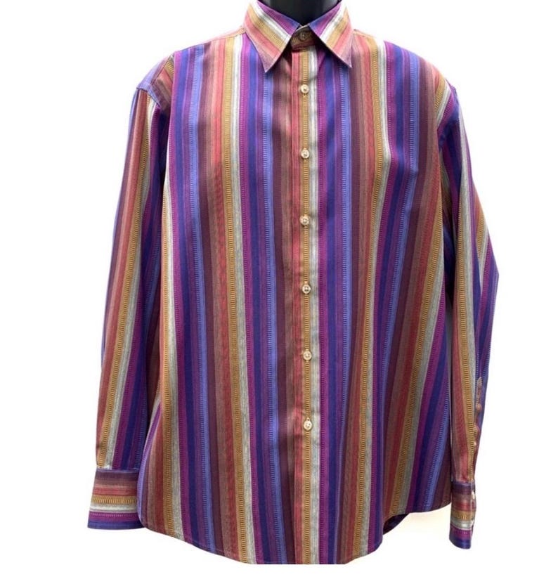 May include: A long-sleeve button-down shirt featuring a vertical striped pattern in shades of purple, red, orange, and light blue. The shirt has a pointed collar, a front button placket with light-colored buttons, and buttoned cuffs on the sleeves.