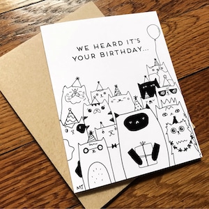 May include: A black and white birthday card with the text "We heard it's your birthday..." and a group of cats wearing party hats and holding a gift.