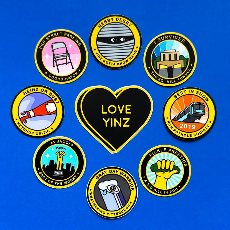 Pu&ograve; includere: Nove adesivi rotondi con contorni neri e testo giallo su sfondo blu. Gli adesivi presentano vari disegni e testi, tra cui "Love Yinz", "Heinz or Bust", "Best in Show", "Nebby Debby", "Gray Day Warrior", "Pickle Prestige", "I Survived", "PGH Street Parking" e "#1 Jagoff".