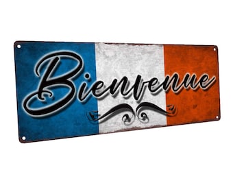 May include: A rusty metal sign with a distressed French flag background and the word "Bienvenue" in black cursive lettering.