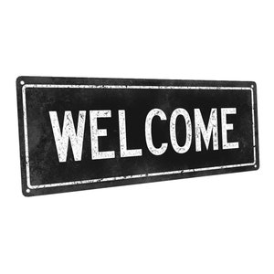 May include: Black metal sign with white lettering that reads "WELCOME". The sign has a distressed, vintage look.
