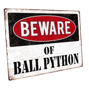 May include: A white metal sign with black and red text that reads "Beware of Ball Python". The sign has a distressed, vintage look.