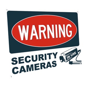 May include: A white sign with a blue and red warning sign that says "WARNING" in white letters. Below the warning sign is the text "SECURITY CAMERAS" in black letters. A black and white security camera with the text "IN USE" is in the bottom right corner of the sign.