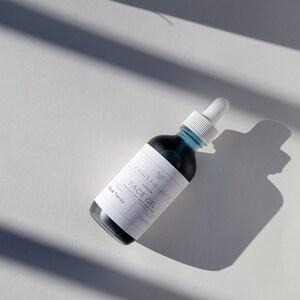 May include: A blue glass bottle with a white label that reads "Cassia Organics Vegan Face Oil Moisturizer and Cleanser Product Blue Tansy 2oz/59ml".