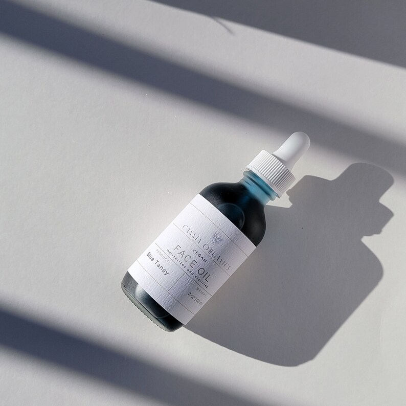 May include: A blue glass bottle with a white label that reads "Cassia Organics Vegan Face Oil Moisturizer and Cleanser Product Blue Tansy 2oz/59ml".