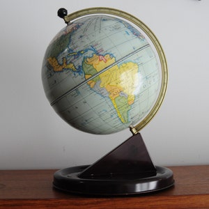 May include: A vintage globe with a blue and green map of the world. The globe is mounted on a black stand with a gold meridian.