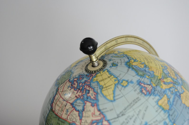 May include: A vintage globe with a blue and yellow map, a gold meridian ring, and a black knob for rotating the globe.