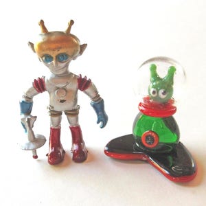 May include: A set of three ceramic mugs with a speckled, matte finish. The mugs are in shades of cream, light gray, and dark gray. Each mug has a simple, minimalist design and a rounded handle.