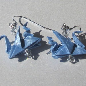 Puede incluir: Un par de pendientes de grulla de origami azul con ganchos plateados y detalles de cristal.