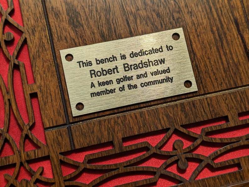 May include: A gold plaque with the inscription "This bench is dedicated to Robert Bradshaw A keen golfer and valued member of the community".