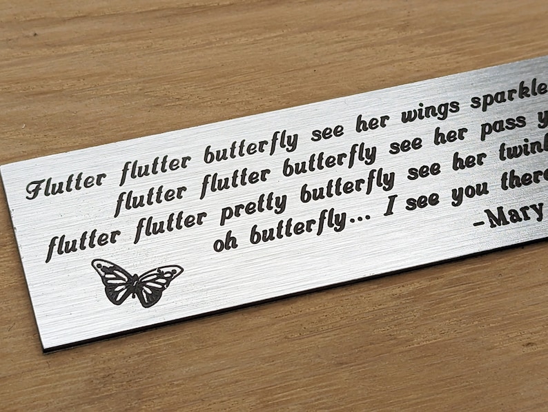 May include: A silver metal plaque with a butterfly design and the text "Flutter flutter butterfly see her wings sparkle flutter flutter butterfly see her pass y flutter flutter pretty butterfly see her twing oh butterfly... I see you there -Mary"