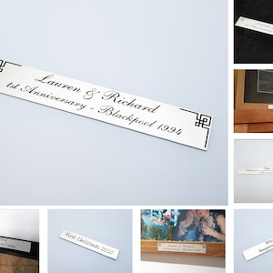 Op de afbeelding: Een verzameling zilveren metalen plaquettes met gegraveerde tekst. De plaquettes zijn rechthoekig en hebben een eenvoudig ontwerp. De tekst op de plaquettes bevat namen, data en speciale gelegenheden. De plaquettes zijn perfect om speciale gebeurtenissen of mijlpalen te herdenken.