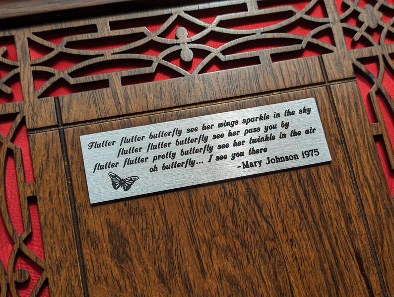 May include: A wooden plaque with a silver metal insert featuring a poem about a butterfly. The poem reads: "Flutter flutter butterfly see her wings sparkle in the sky flutter flutter butterfly see her pass you by flutter flutter pretty butterfly see her twinkle in the air oh butterfly... I see you there -Mary Johnson 1975"