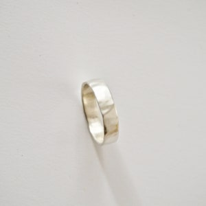 May include: A silver hammered band ring.