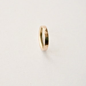 May include: A gold-coloured ring with a hammered texture. The ring is a simple band design, suitable for everyday wear. The ring is shown against a white background.