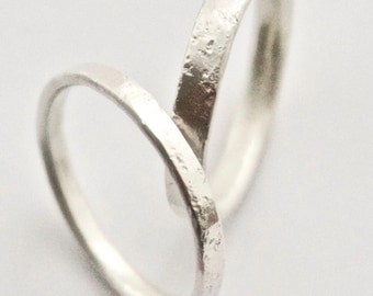 May include: Two silver rings, one with a smooth finish and the other with a textured finish, are intertwined.