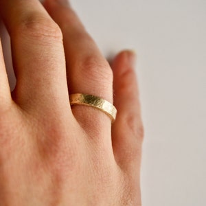 A gold band ring with a textured surface.