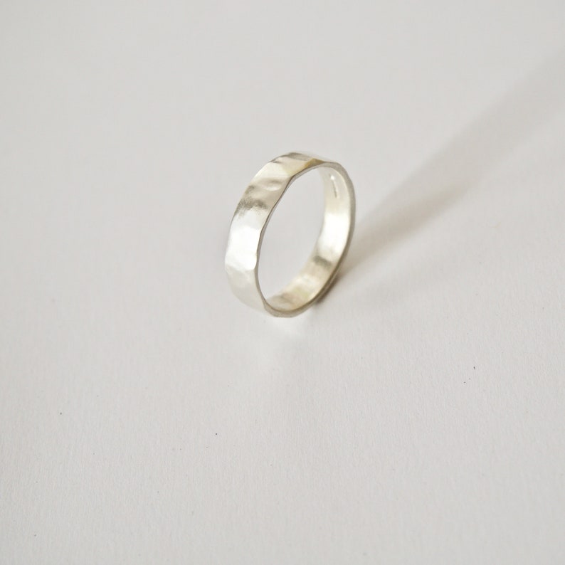 May include: A silver hammered band ring. The ring is thick and has a textured surface.