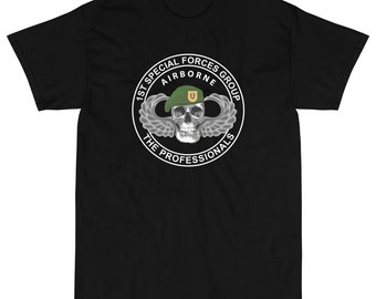 Puede incluir: Camiseta negra con un gráfico circular blanco que presenta una calavera con un gorro verde y un parche amarillo. El texto alrededor de la calavera dice "1st Special Forces Group Airborne The Professionals".