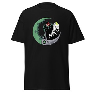 Könnte beinhalten: Schwarzes T-Shirt mit einem grafischen Design. Das Design zeigt eine Figur mit rotem Gesicht, ein skelettartiges Wesen und einen grünen Halbmond. Die Figur hält eine Waffe. Das Design ist in Grün, Weiß, Grau und Schwarz gehalten.