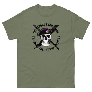 May include: A green t-shirt with a black skull wearing a black beret with a military patch. The skull is surrounded by a circle with the text "The Strong Shall Stand The Weak Fall By The Wayside".