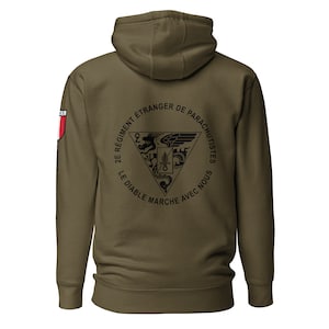 May include: A green hooded sweatshirt with a black circle on the back. The circle contains a black and white emblem with the text "2e Régiment Étranger de Parachutistes Le Diable Marche Avec Nous".