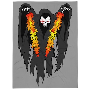Puede incluir: Una manta gris con un gráfico de tres figuras encapuchadas con caras de calavera y acentos de color naranja y amarillo fuego. Las figuras están envueltas en capas negras, con llamas que se extienden por el frente. El diseño está centrado en la manta.