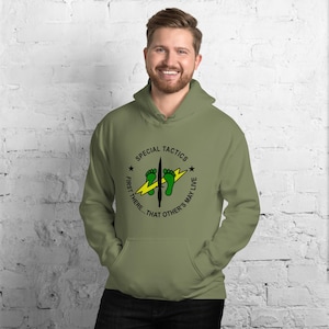 May include: Olive green hooded sweatshirt with a front graphic. The graphic features the words "SPECIAL TACTICS" in a circle, with a lightning bolt, footprints, and the text "FIRST THERE... THAT OTHER'S MAY LIVE".