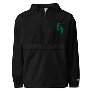 May include: Black windbreaker jacket with a hood and a half-zip closure. The jacket features a green footprint design on the upper left chest. The jacket has a front pocket and the Champion logo on the lower right sleeve.