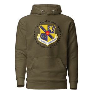 May include: A green hooded sweatshirt with a black and white circular graphic of the 501st Tactical Missile Wing, RAF Greenham Common UK.