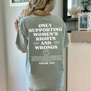 May include: Sage green t-shirt with a white graphic print that reads "Only Supporting Women's Rights Good Vibes And Wrongs" with a smiley face below the text. The text also includes the words "Good Vibes".