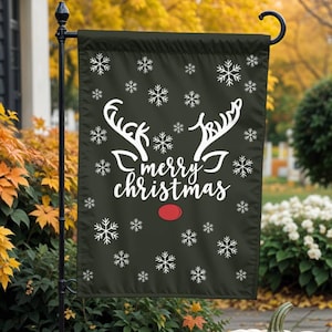 Peut inclure: Un drapeau de jardin noir avec le texte blanc "merry christmas" et un motif de renne avec des flocons de neige. Le drapeau est exposé à l'extérieur avec des citrouilles et des feuilles d'automne.