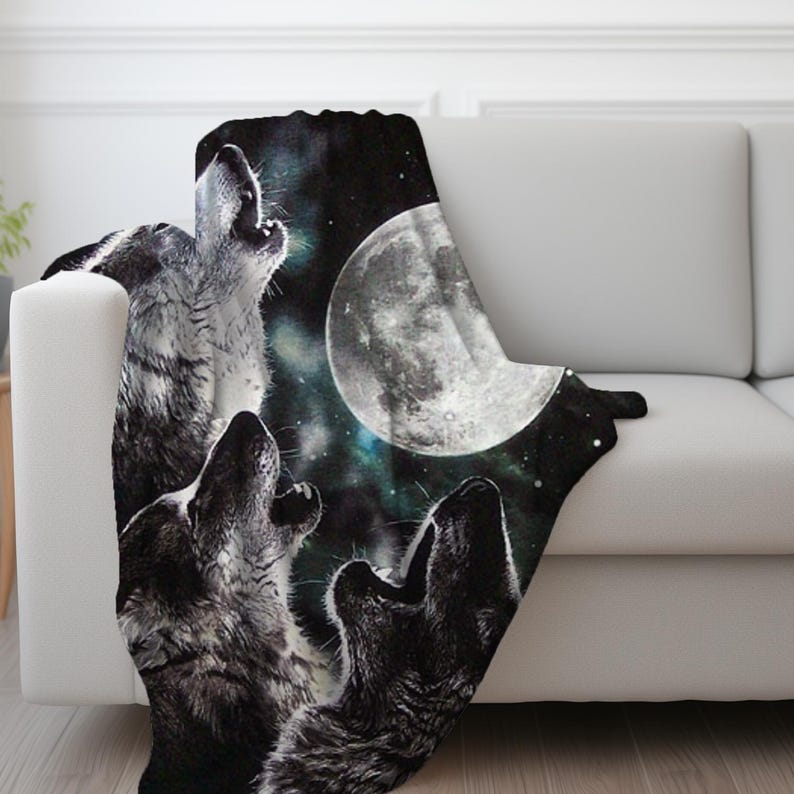 May include: A black and white blanket featuring a nighttime scene with three wolves howling at a full moon. The blanket has a dark background with stars and a nebula effect, creating a dramatic and nature-inspired design.