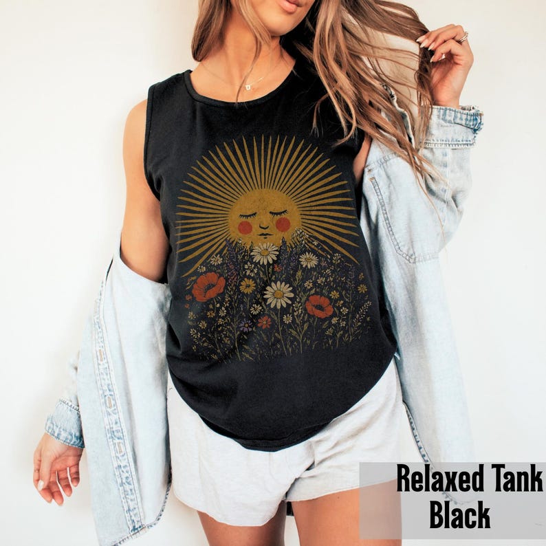 Puede incluir: Camiseta sin mangas negra relajada con un gr&aacute;fico de sol con una cara y elementos florales. El sol tiene una cara y rayos de color amarillo dorado. Las flores incluyen amapolas rojas y margaritas blancas. El texto "Relaxed Tank Black" est&aacute; en la parte inferior.