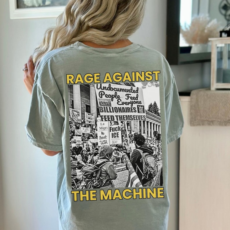 Puede incluir: Camiseta verde claro con un gr&aacute;fico en la espalda. El gr&aacute;fico es una imagen en blanco y negro de una protesta con las palabras "RAGE AGAINST THE MACHINE" y otro texto. La camiseta es de estilo casual.