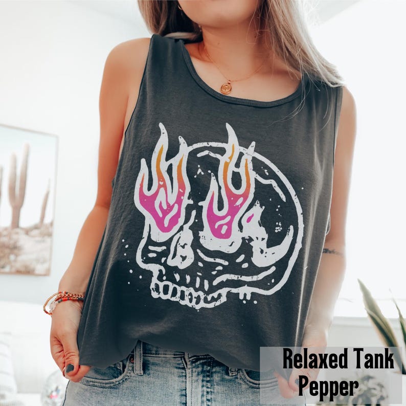 May include: Dark gray tank top with a white skull graphic featuring pink and orange flames. The text "Relaxed Tank Pepper" is at the bottom of the image. The tank top is sleeveless.