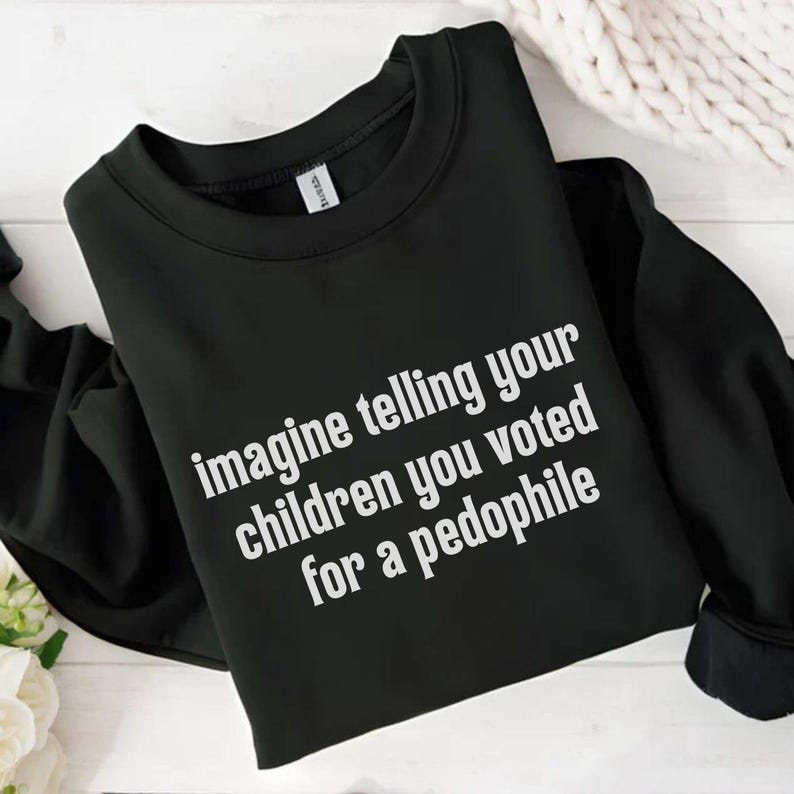 May include: Black crew neck sweatshirt with white text that reads "imagine telling your children you voted for a pedophile". The sweatshirt is folded on a white wooden surface.