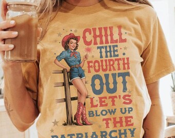 Puede incluir: Camiseta de color amarillo mostaza con un gráfico de una mujer con sombrero y botas de vaquero, sosteniendo una bengala. El texto en la camiseta dice "CHILL THE FOURTH OUT LET'S BLOW UP THE PATRIARCHY."
