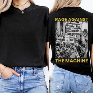 May include: Black t-shirt with the text "RAGE AGAINST THE MACHINE" and a graphic of a protest scene. The back of the shirt features the text "Undocumented People Feed Everyone Billionaires Feed Themselves".