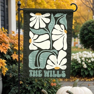 Puede incluir: Una bandera de jardín verde y blanca con un diseño floral y el texto "The Wills" en una fuente retro.