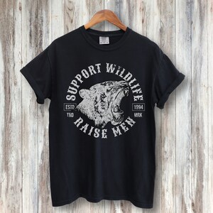 May include: Black t-shirt with a white graphic print of a roaring tiger head inside a circle. The circle has the text "Support Wildlife" at the top, "Raise Men" at the bottom, "Estd. 1994" on the right, and "TKD MRK" on the left.