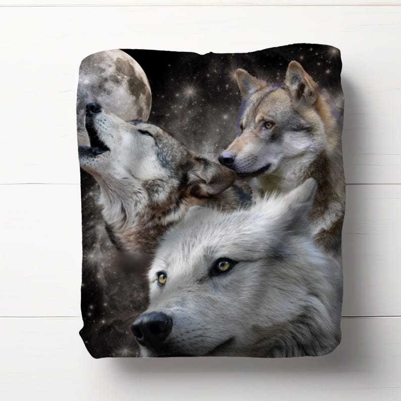 May include: A plush blanket featuring a nighttime scene with three wolves. One wolf is howling at a full moon, while the others look on. The background is a starry night sky with a dark color palette.