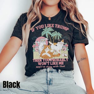 May include: A black t-shirt with a graphic print of cats and palm trees. The text on the shirt reads "If you like Trump then you probably won't like me and I'm okay with that."