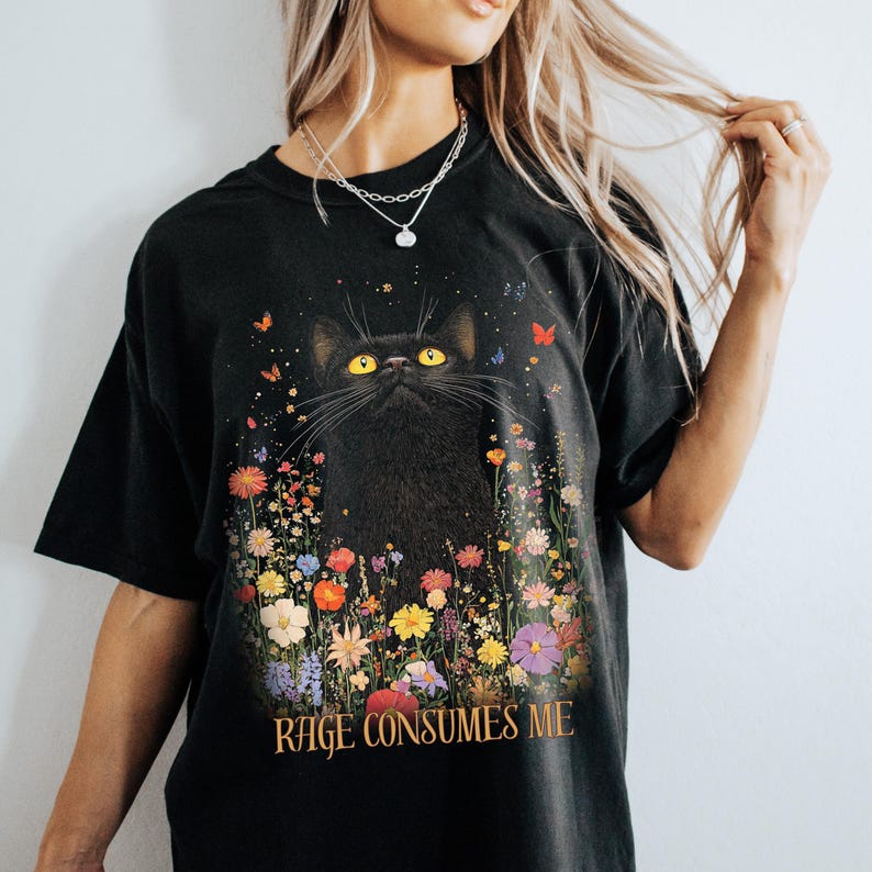 May include: Black t-shirt with a black cat surrounded by colorful flowers and the text "Rage Consumes Me".