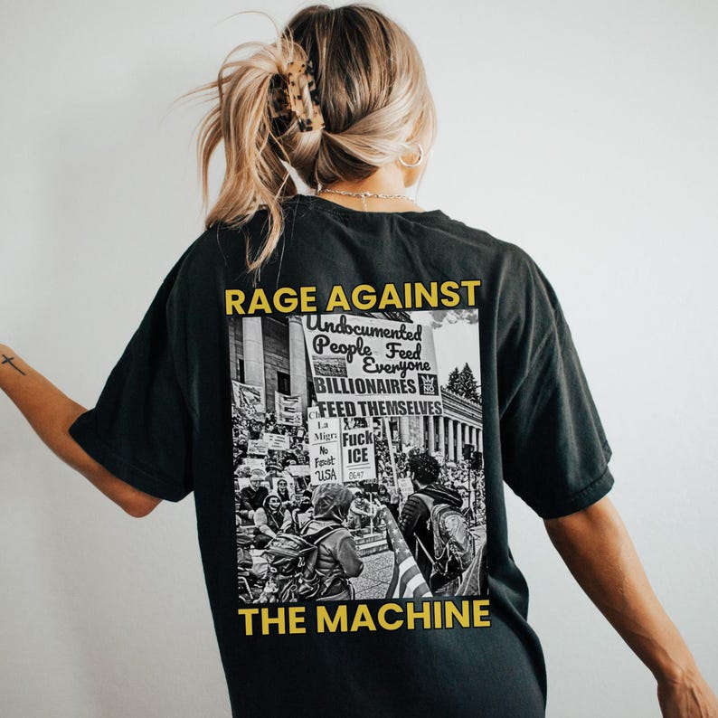 May include: Black t-shirt with a graphic that reads "RAGE AGAINST THE MACHINE." The graphic includes the text "Undocumented People Feed Everyone Billionaires Feed Themselves" over a black and white image of a protest.